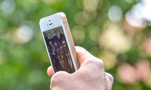 Anonymous hand holding iPhone to take selfie on graduation day
