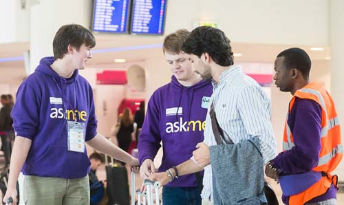Students in University of Manchester hoodies helping students arriving at an airport