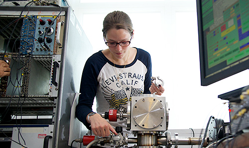 A female postgraduate student looking down at the machinery she is operating