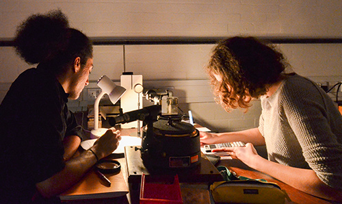 Two undergraduate students focusing under low light while conducting lab experiment