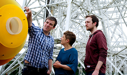 Three students stood in front of the Lovell Telescope