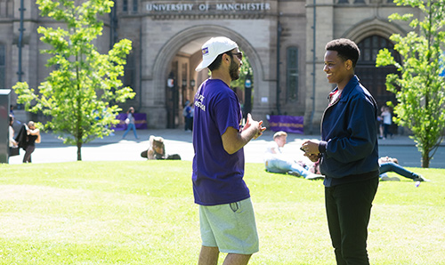 Male student talking to prospective student on lawn in front of Whitworth Hall