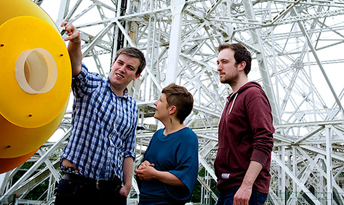Three students stood in front of the Lovell Telescope