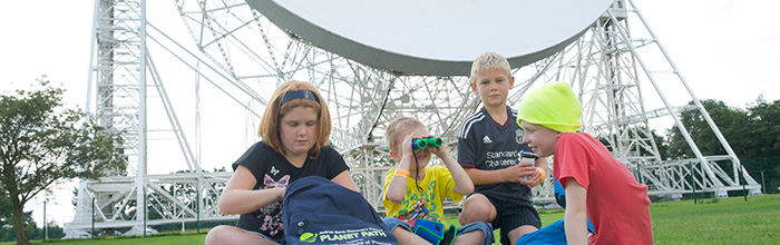 children on the grass in front of the Lovell Telescope