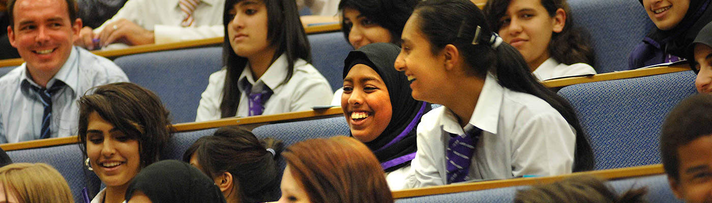 Secondary school children laughing while sitting in a lecture