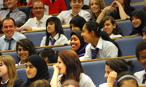 Secondary school children laughing while sitting in a lecture