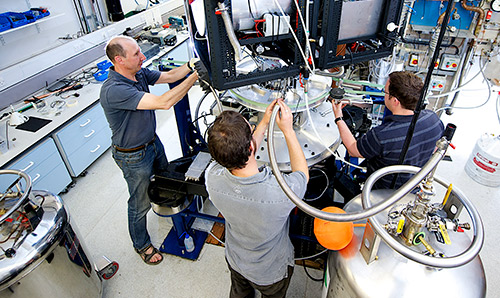 Three researchers operating equipment in the cryostat laboratory