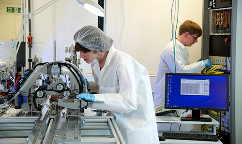 Two PhD students in white lab coats conducting separate experiments in lab