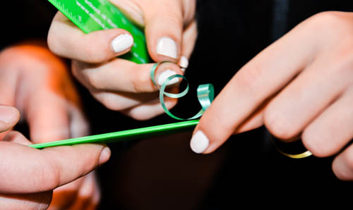 a close up of hands curling ribbon with a pair of scissors