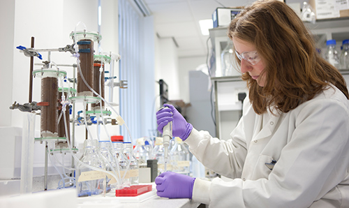 A female researcher in lab coat performing an experiment