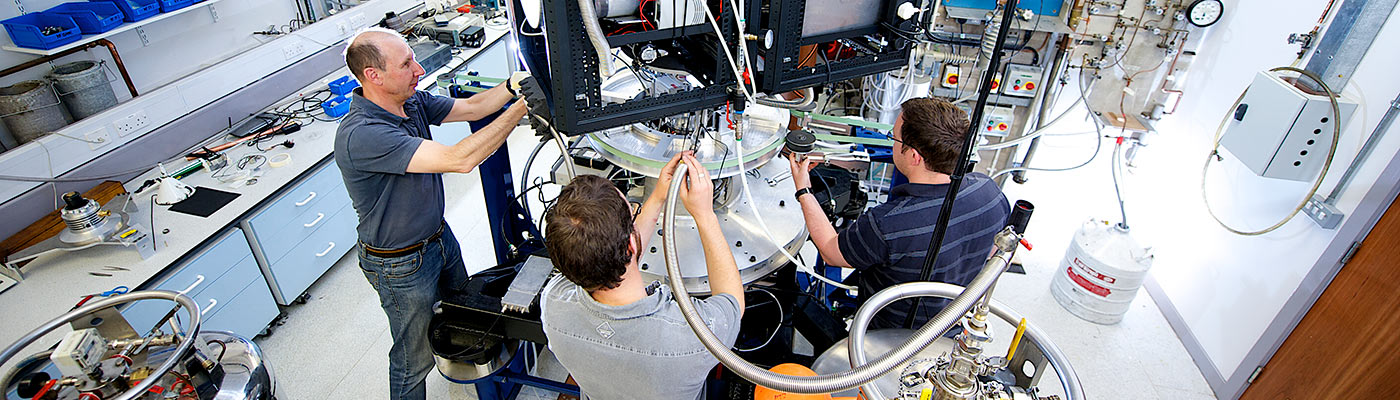 Three male researchers using equipment in the cryostat lab