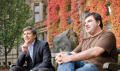 Two men sitting on a bench outside The University of Manchester