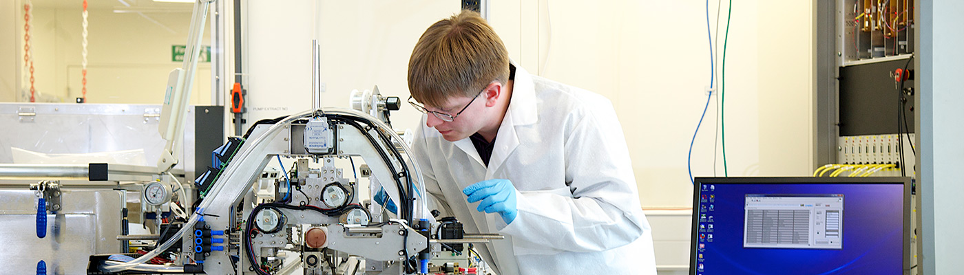 Researcher examining equipment in a clean room