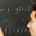 A researcher writing out a formula on a blackboard