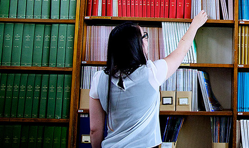 A female researcher reaching for a book in the library at Jodrell Bank Observatory