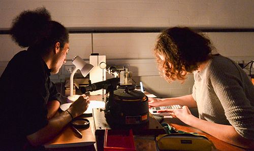 Two undergraduate students focusing under low light while conducting lab experiment