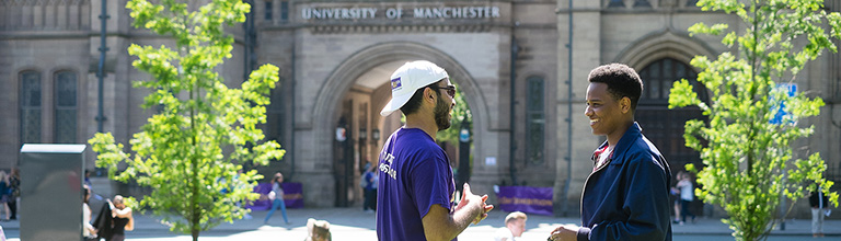 Male student talking to prospective student on lawn in front of Whitworth Hall