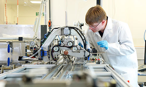 A researcher examining equipment in a clean room