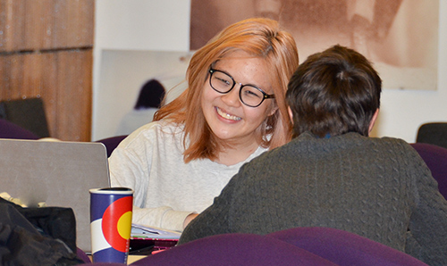 A male and female student in conversation in the library