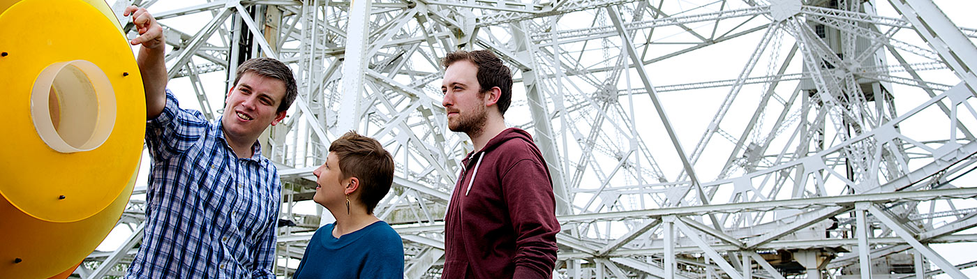 Three students stood in front of the Lovell Telescope