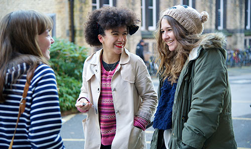 Three female students smiling and laughing together